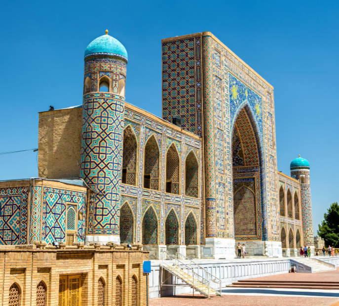 Historic Islamic architecture with mosaic walls and turquoise domes under a clear blue sky.